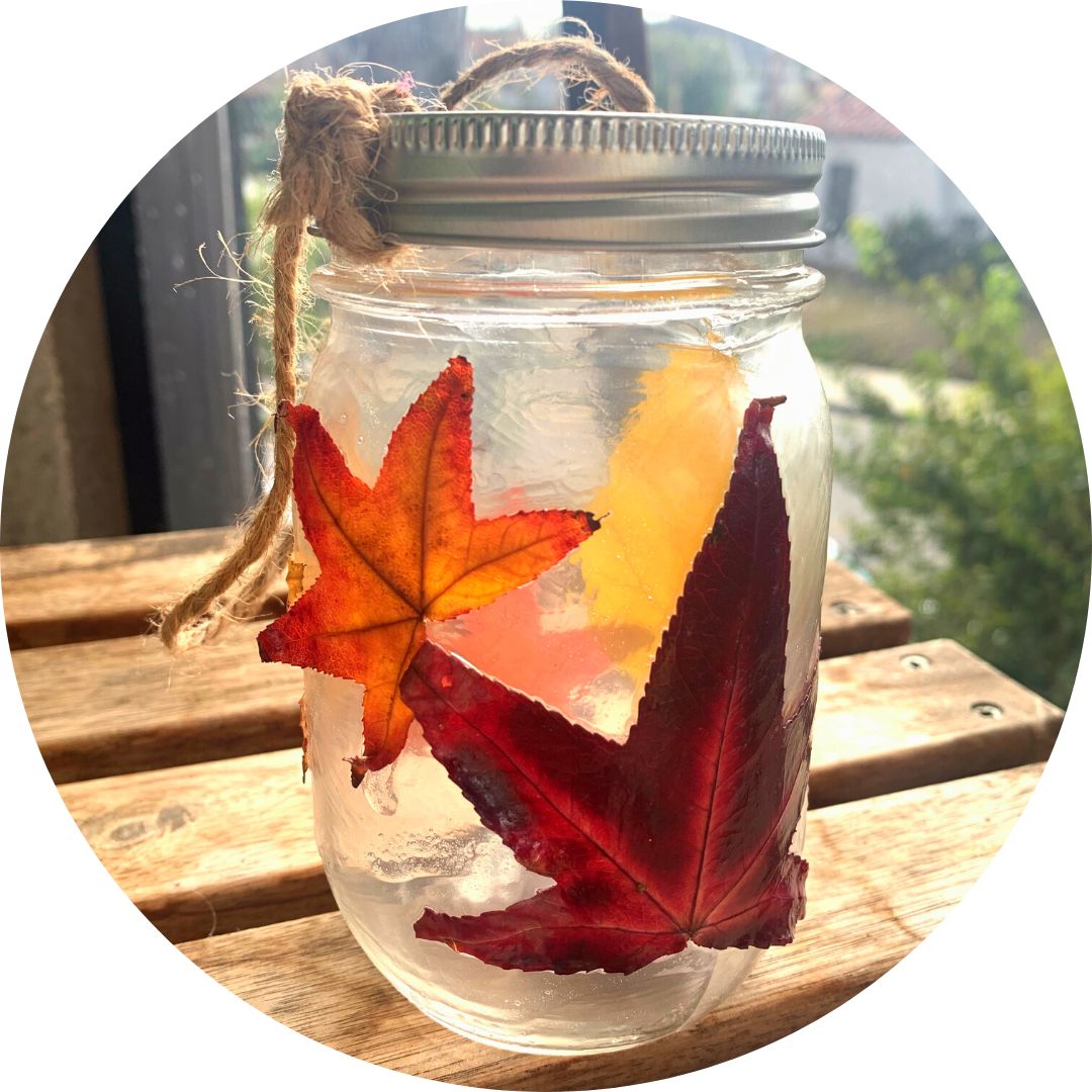 A mason jar lantern with autumn leaves on the outside