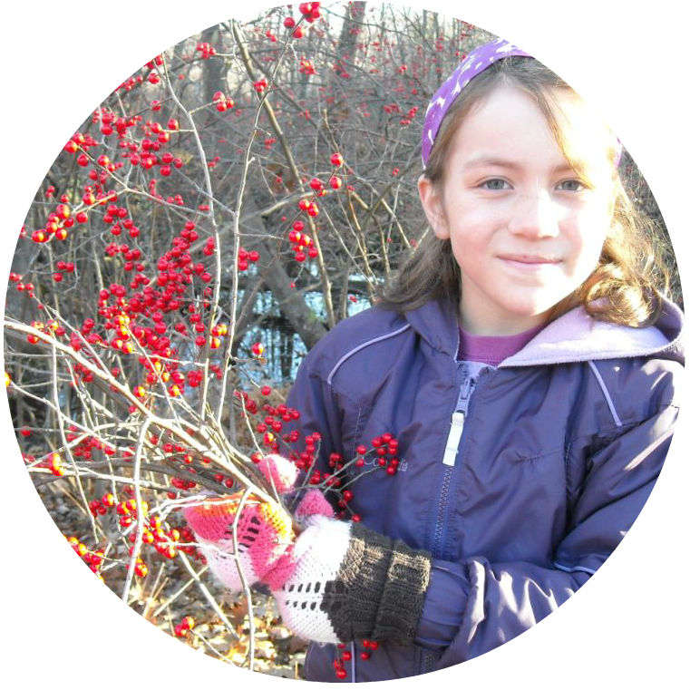 Young girl outside in winter holding branches of winterberry to make a wreath