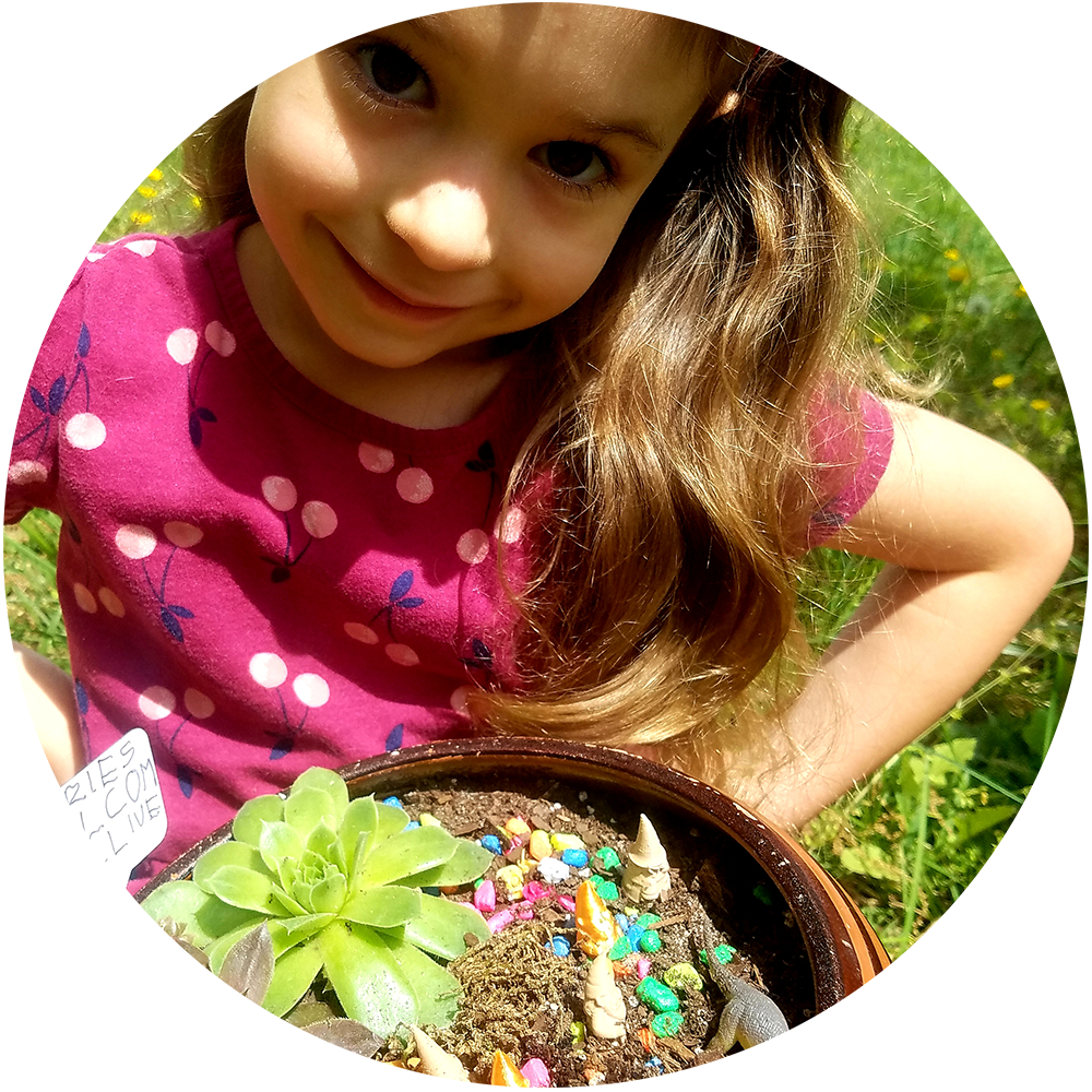 Child holding a container with small plants and fairy figures