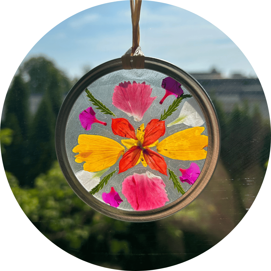 A handmade sun catcher in a window, with colorful flowers.
