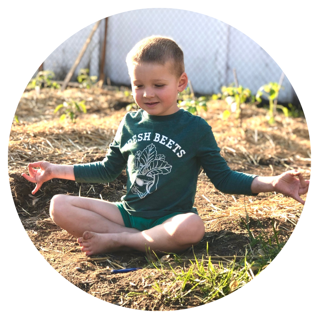A child sitting with crossed legs and their arms out in a meditative pose